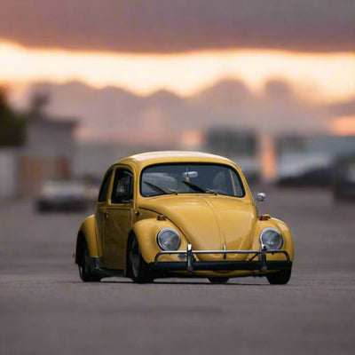 Yellow vintage car on a road with a sunset or sunrise in the background